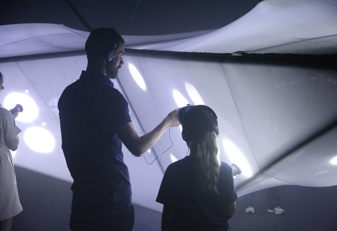 A dark room with people looking at lights in the shape of a plane