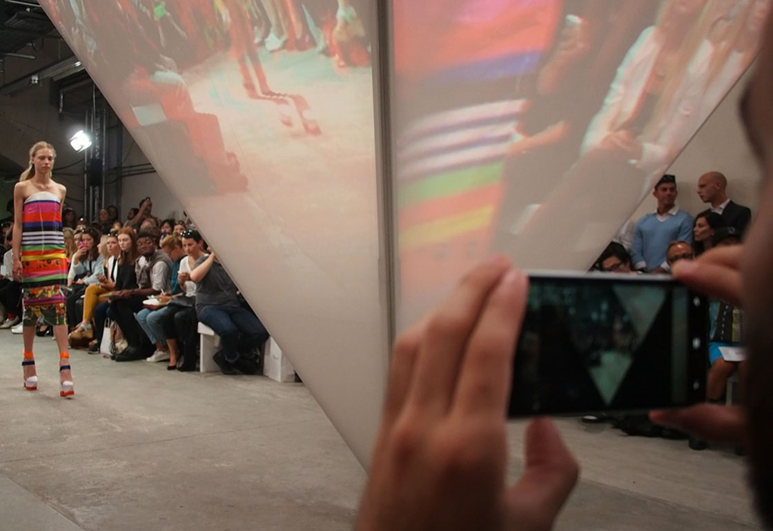 Model in blue clothes in front of pyramid screen