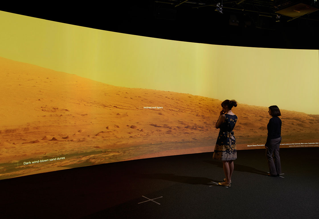 A projection of the martian landscape in the exhibition with people looking at it