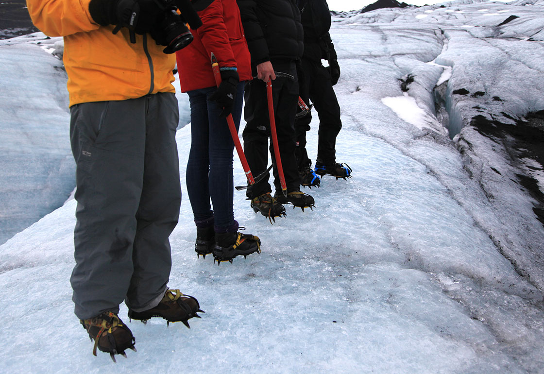 4 people's legs standing on a glacier