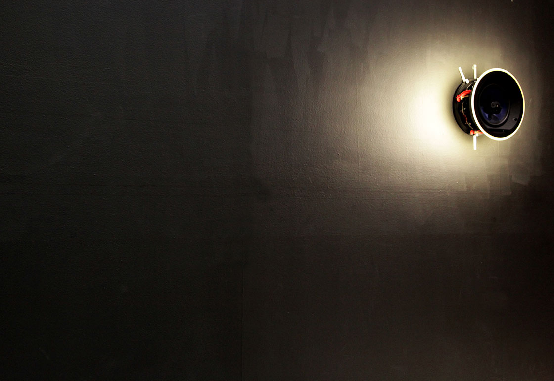 Speakers on a wall with one with a halo of light surrounding it